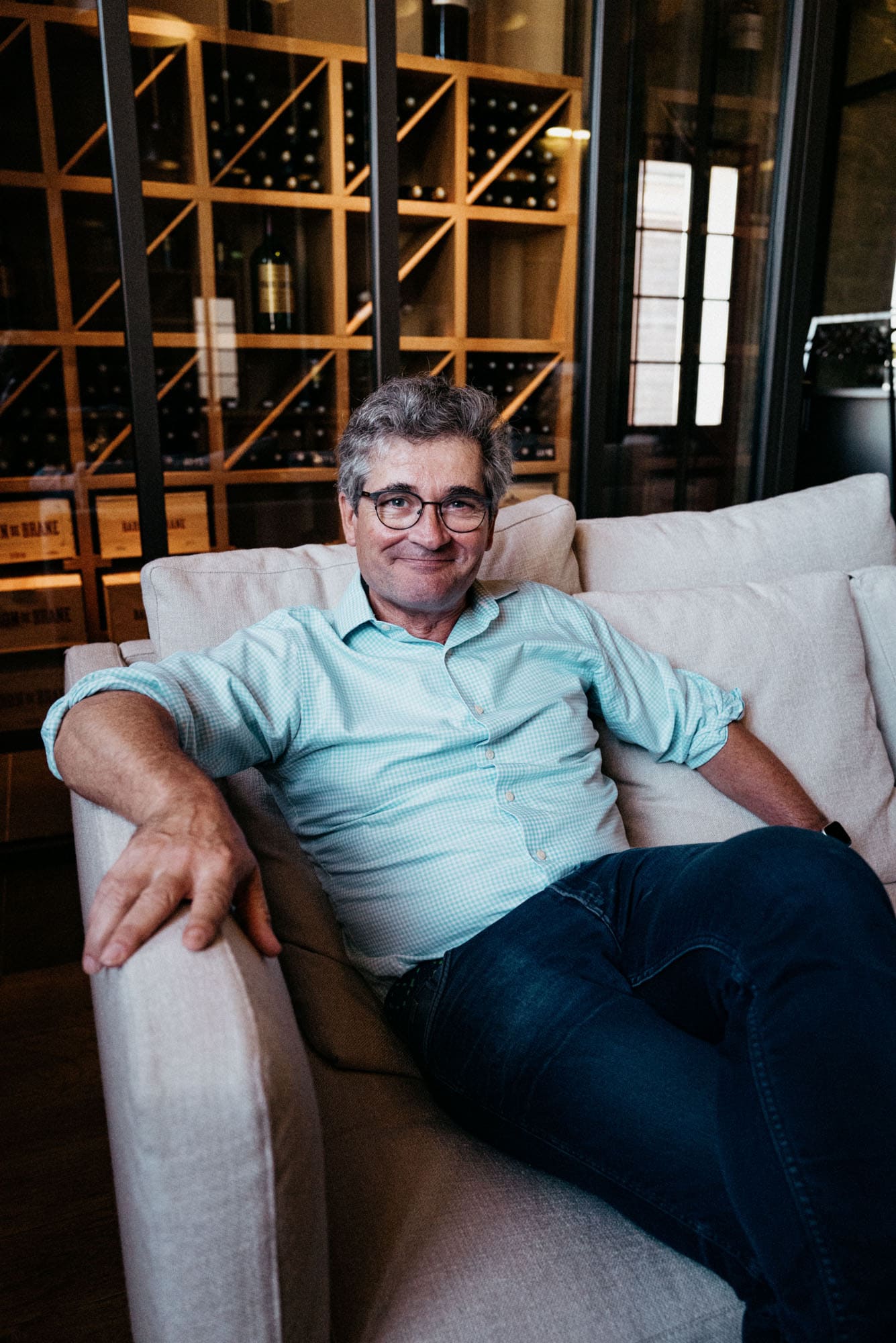 Portrait of Henri Lurton sitting on sofa at Château Brane-Cantenac.