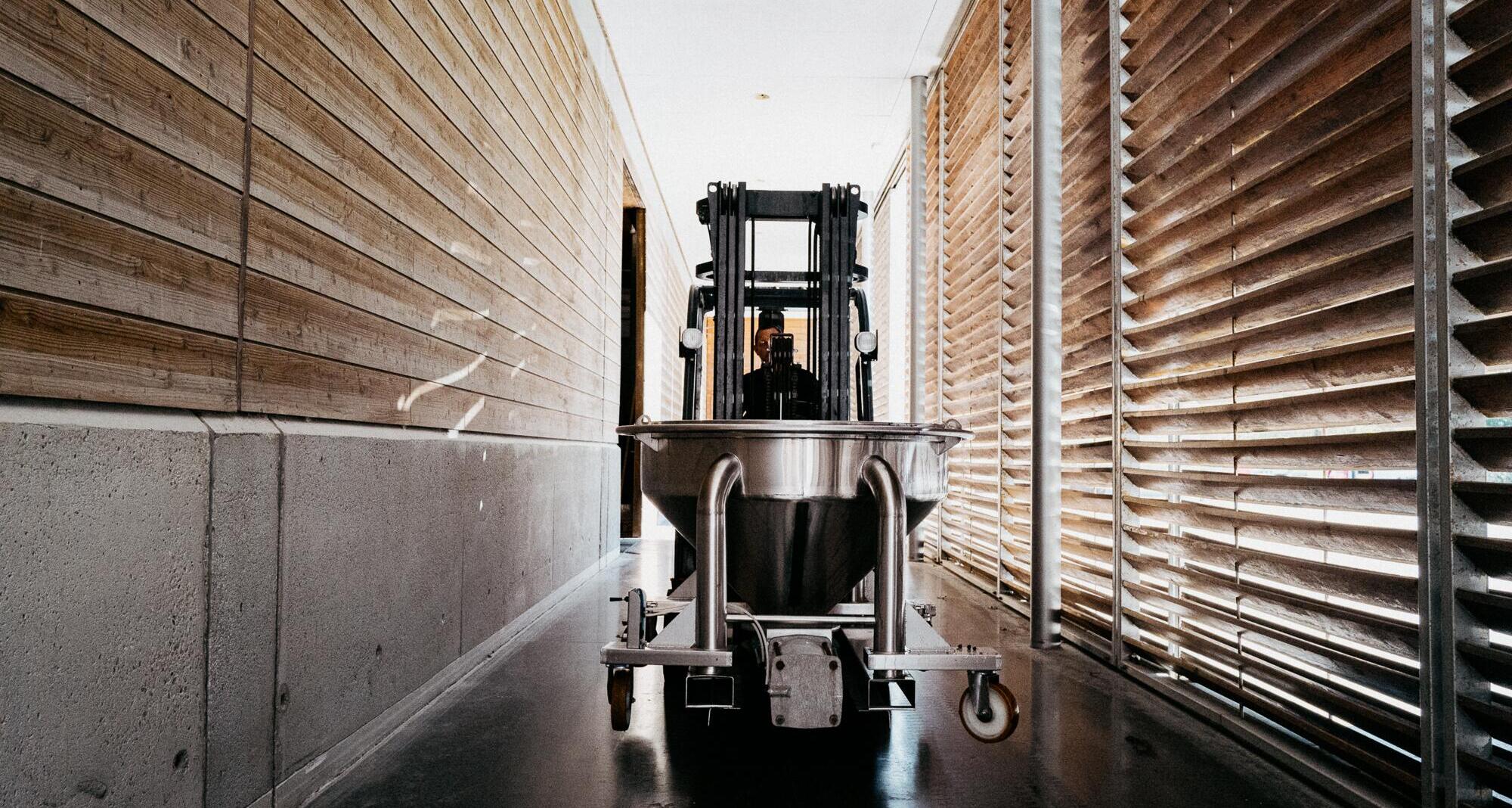 Wide angle of forklift truck carrying small vat into the winery at Chateau Brane-Cantenac.