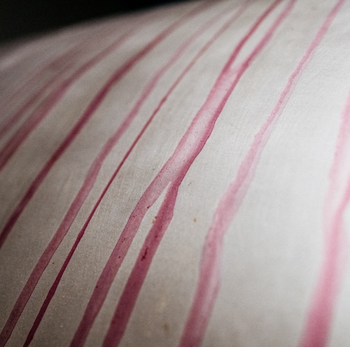 Close up of pink streaks of wine on the outer metal surface of a grape pressing machine.