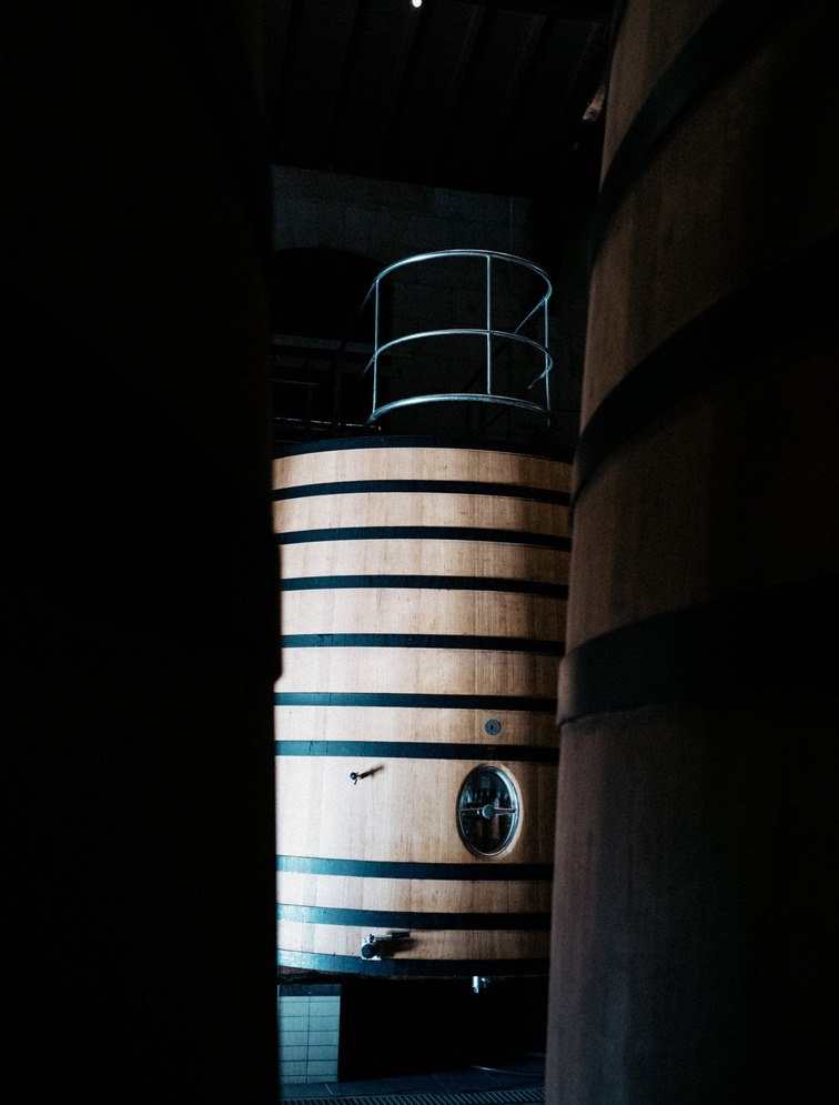 A wooden vine vat lit by light entering the winery at Chateau Brane-Cantenac.
